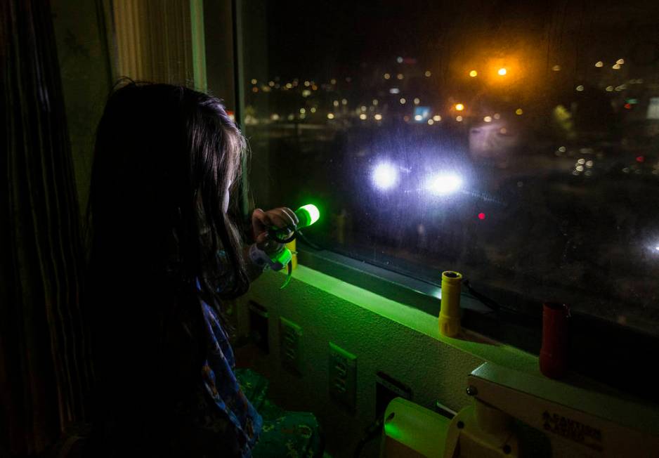 Alicia Langoria-Buffington, 5, shines a flashlight back at a crowd of people in the parking lot ...