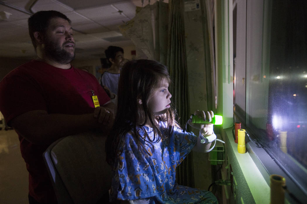 Alicia Langoria-Buffington, 5, in front of her dad David Langoria-Buffington, shines a flashlig ...