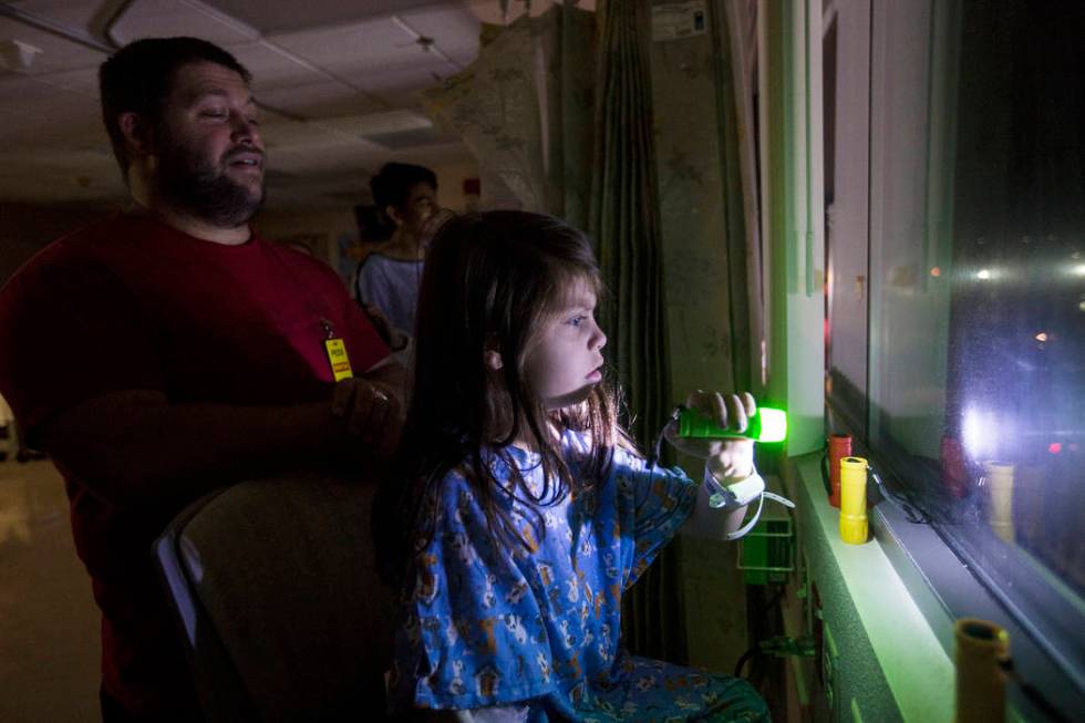 Alicia Langoria-Buffington, 5, in front of her dad David Langoria-Buffington, shines a flashlig ...