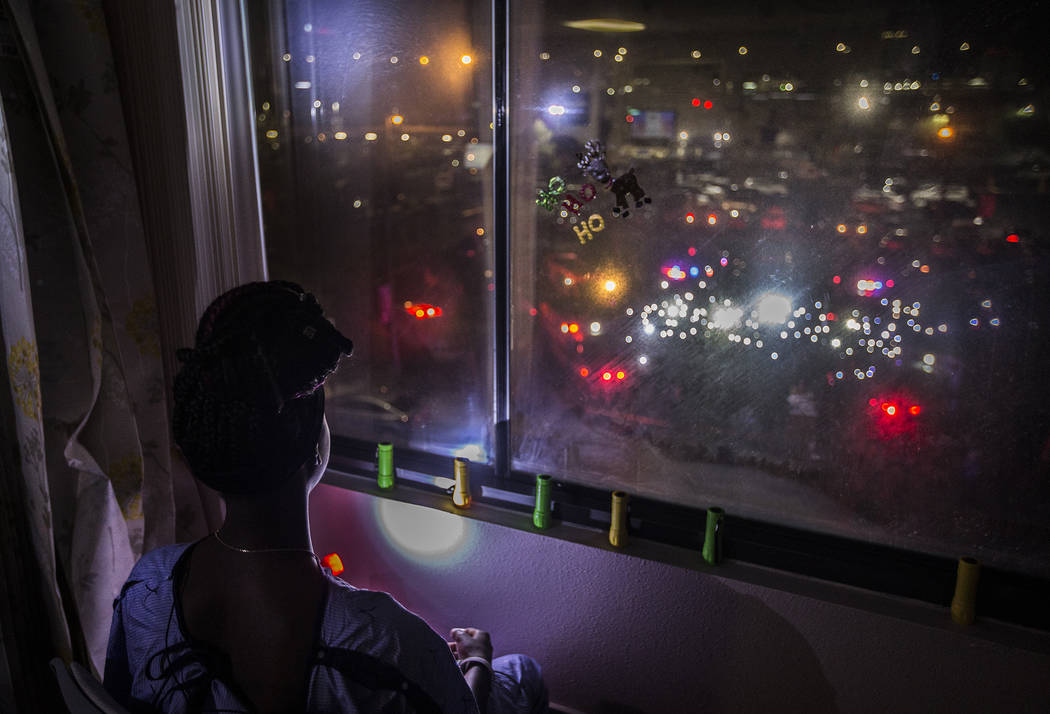 Zion Green, 12, shines a flashlight back at a crowd of people in the parking lot flashing light ...