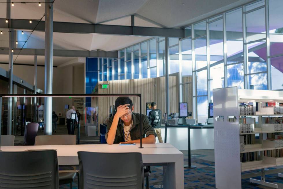 John Ollado, 20, watches a video on his phone at the East Las Vegas Library in Las Vegas on Tue ...