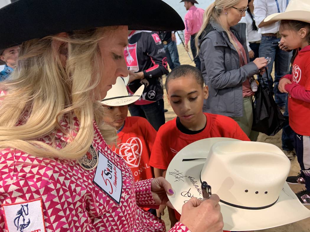 Wrangler NFR barrel racer Amberleigh Moore pens her autograph on a cowboy hat for one of the sp ...