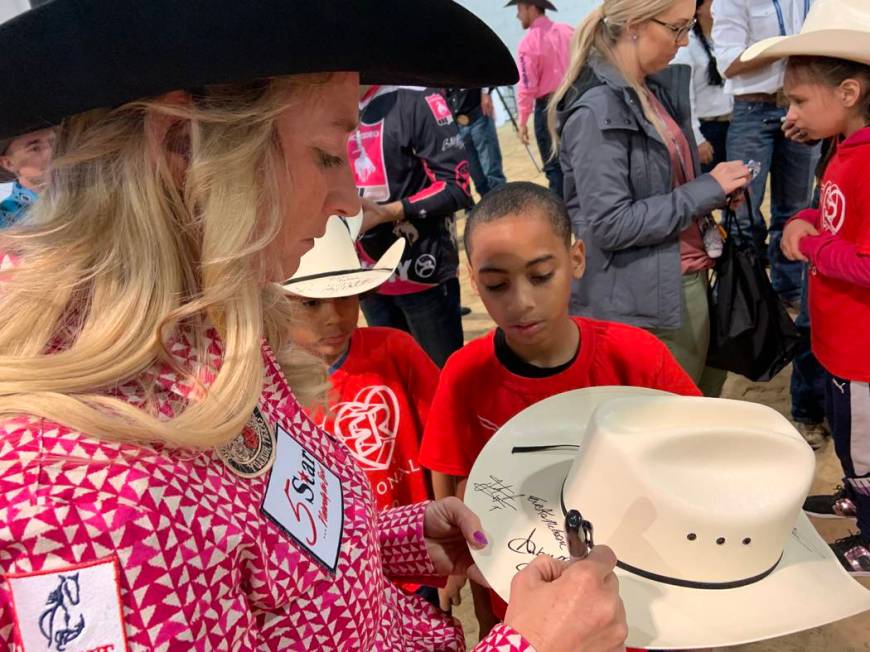 Wrangler NFR barrel racer Amberleigh Moore pens her autograph on a cowboy hat for one of the sp ...