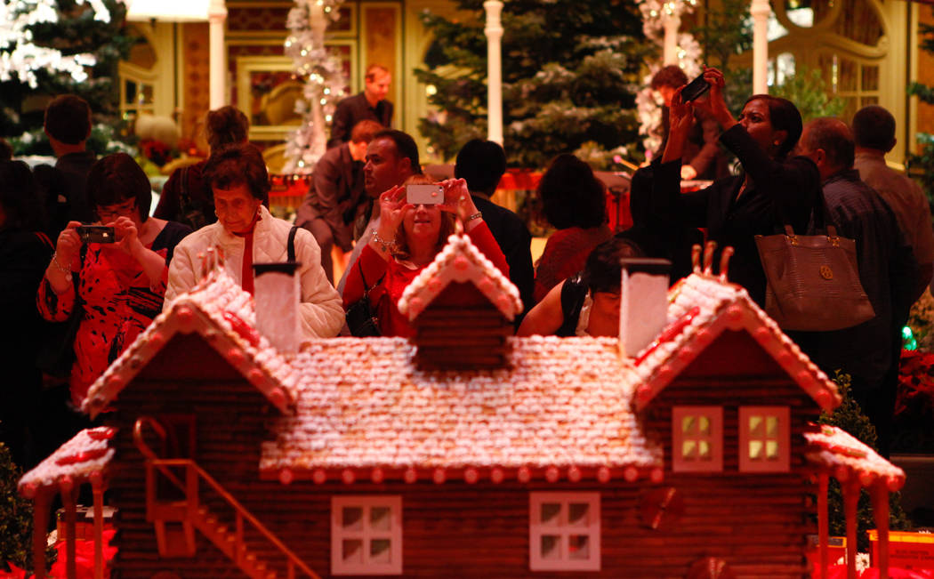 People take pictures of a miniature Christmas village after the Christmas tree lighting at the ...