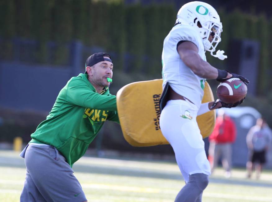 Oregon Offensive Coordinator Marcus Arroyo blocks running back Taj Griffin during a passing dri ...