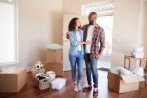 Happy Couple Surrounded By Boxes In New Home On Moving Day