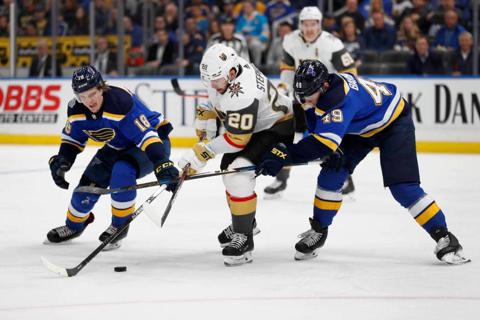 Vegas Golden Knights' Chandler Stephenson (20) reaches for a puck between St. Louis Blues' Robe ...