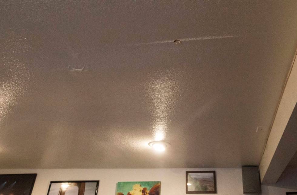 A hole and markings are left from a leak in the living room ceiling in the rental home of John ...