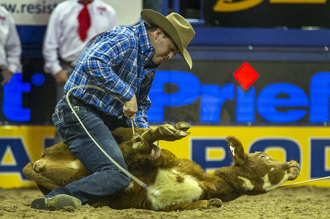 Tyler Milligan of Pawhuska, Okla., ties a calf while on a first place time of 7.50 seconds in T ...