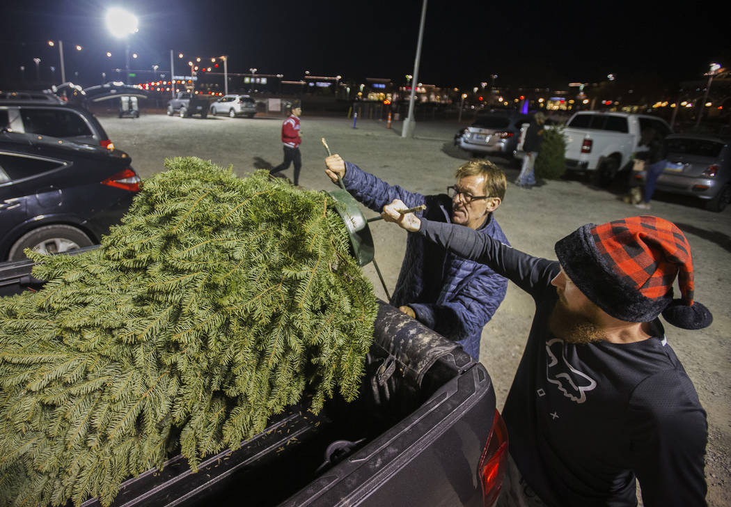 Jay Rogers, middle, helps Justin Critser load a Christmas tree into Crister's truck on Wednesda ...