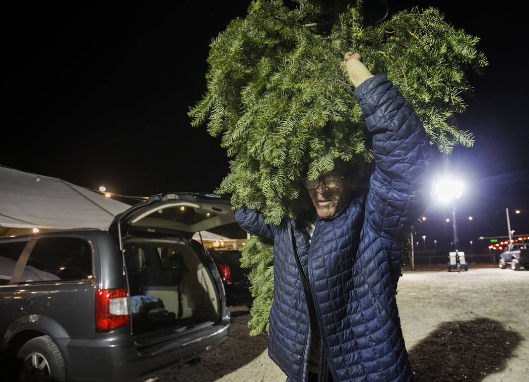 Jay Rogers carries a newly bought Christmas tree to a customers car on Wednesday, Dec. 11, 2019 ...
