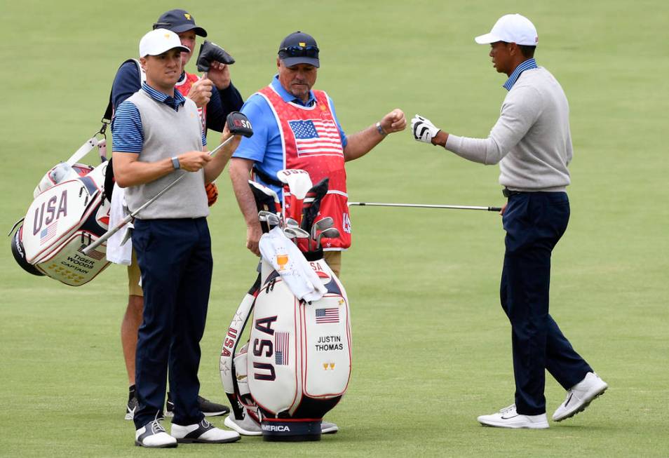 U.S. team player and captain Tiger Woods, right, and playing partner Justin Thomas, left, walk ...