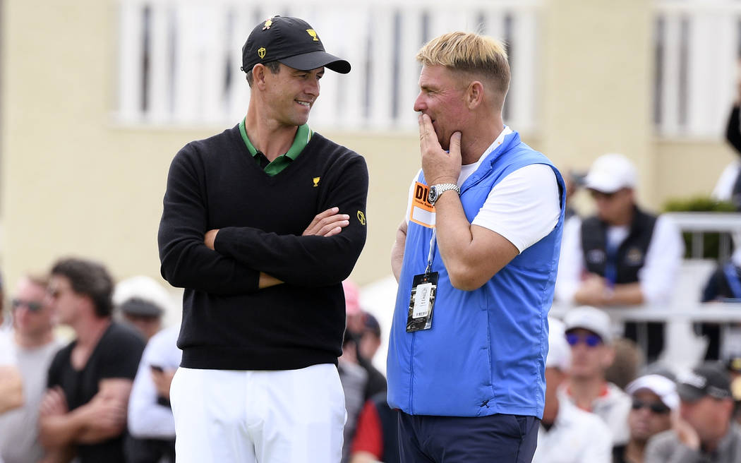 International team player Adam Scott of Australia, left, talks with former cricket player Shane ...