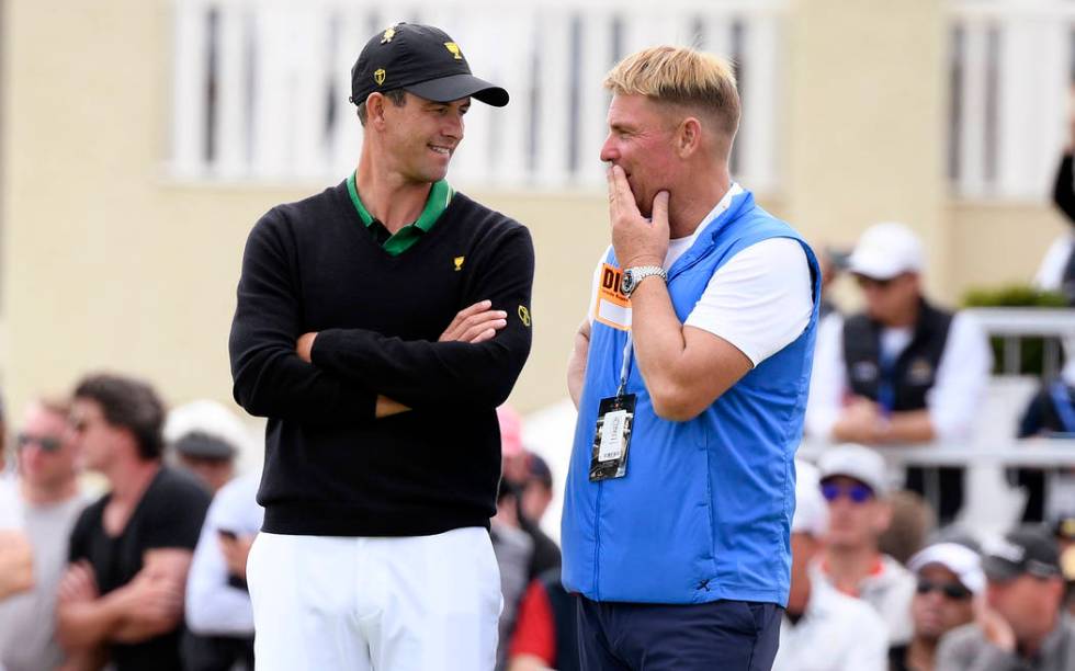 International team player Adam Scott of Australia, left, talks with former cricket player Shane ...