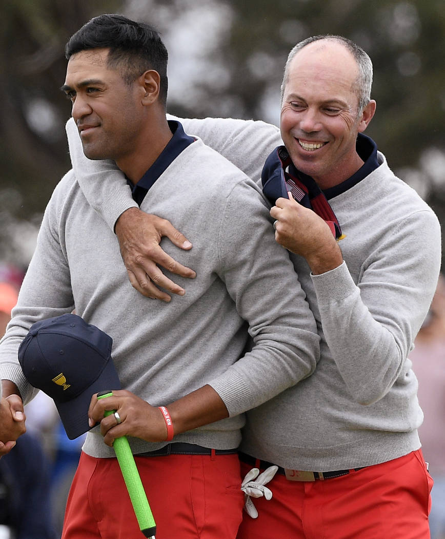 U.S. team player Tony Finau, left, is embraced by partner Matt Kuchar after winning the 18th ho ...