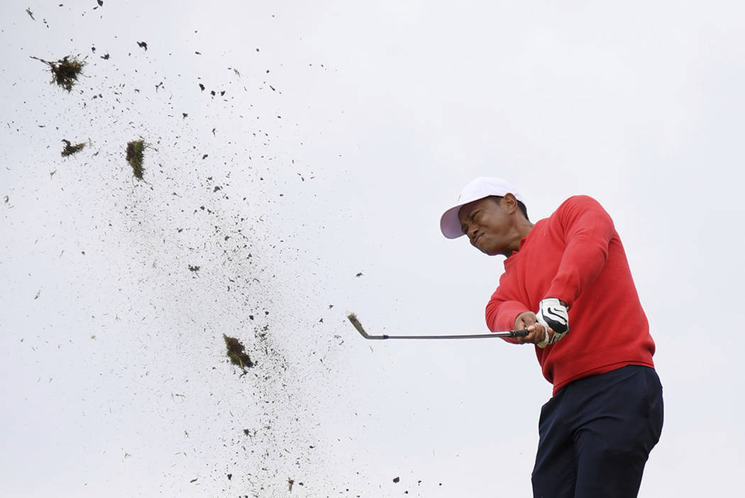 Debris flies as U.S. team player and captain Tiger Woods plays a shot on the 10th raiway in his ...