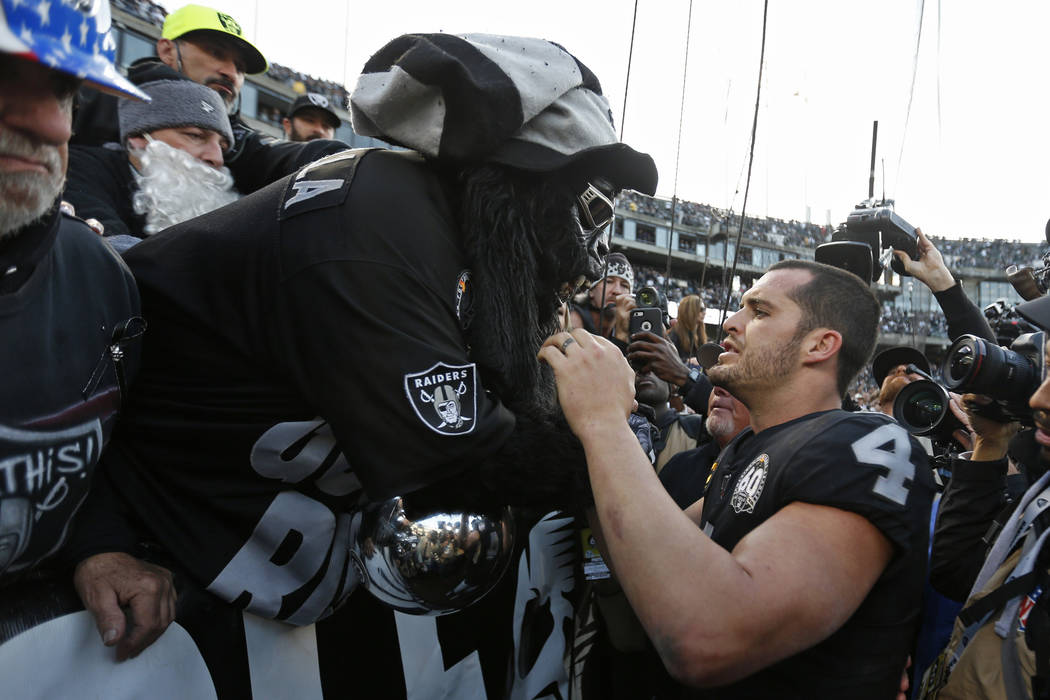 Oakland Raiders quarterback Derek Carr (4) is met by Gorilla Rilla in "The Black Hole" at the e ...