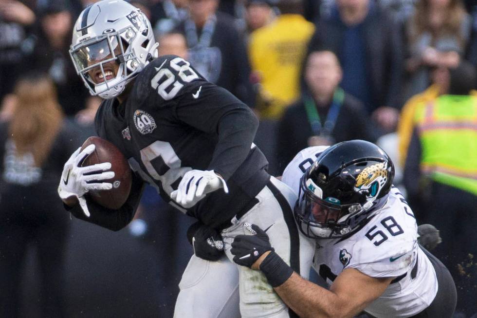 Oakland Raiders running back Josh Jacobs (28) drags Jacksonville Jaguars outside linebacker Aus ...