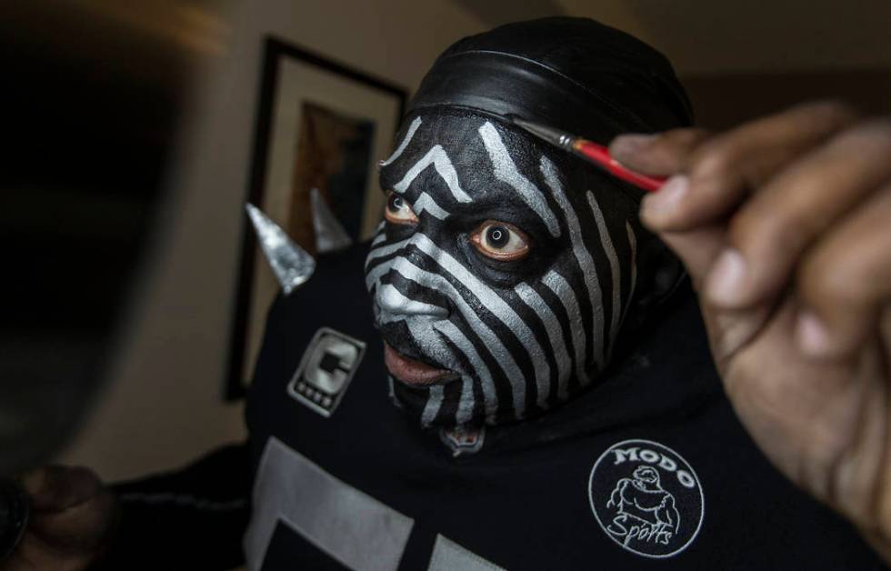 Raiders super fan Wayne Mabry, known as "Violator," applies makeup in his hotel room ...