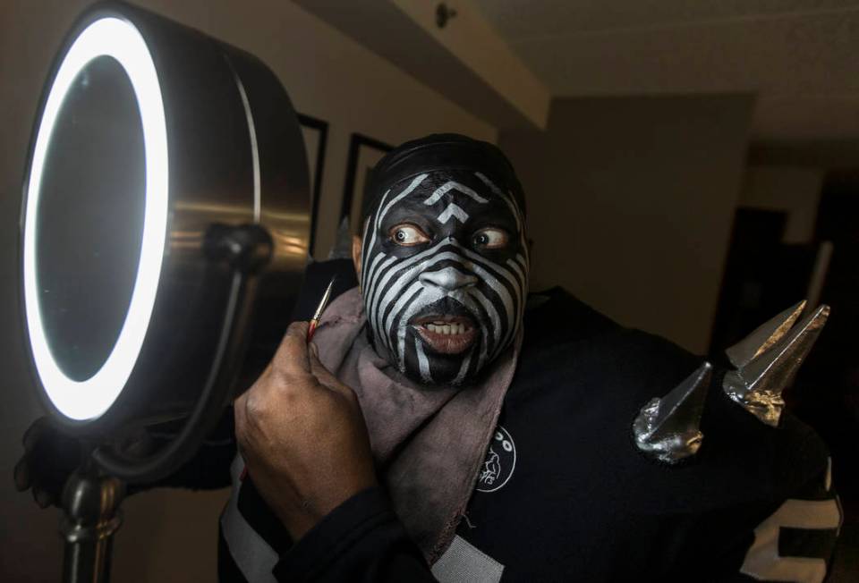 Raiders super fan Wayne Mabry, known as "Violator," applies makeup in his hotel room ...