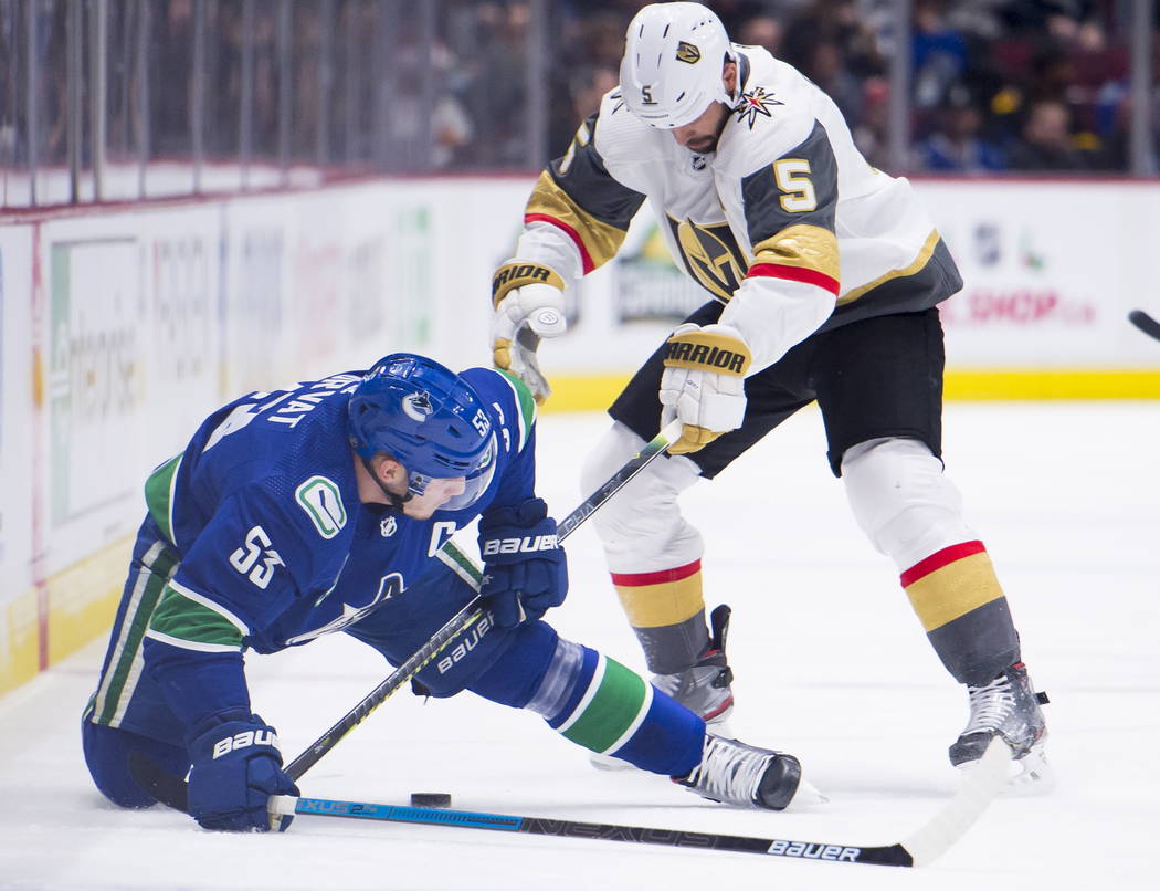 Vancouver Canucks center Bo Horvat (53) fights for control of the puck with Vegas Golden Knight ...