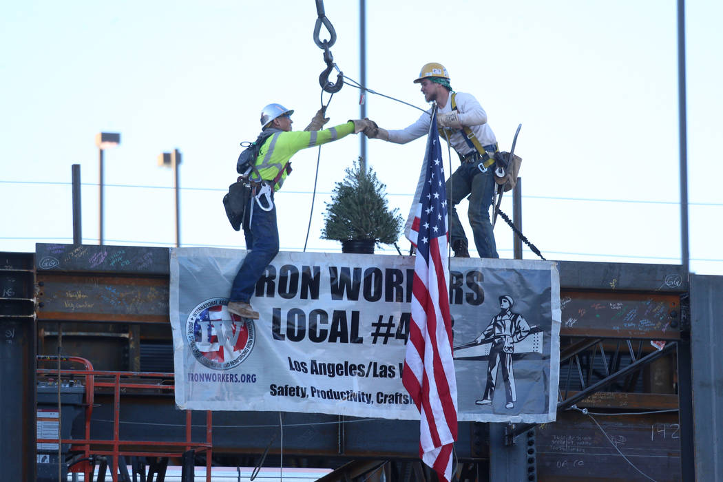 Workers shake hands after place during a topping-off ceremony for the Expo at World Market Cen ...