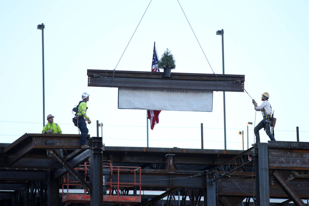 Workers move a beam into place during a topping-off ceremony for the Expo at World Market Cente ...