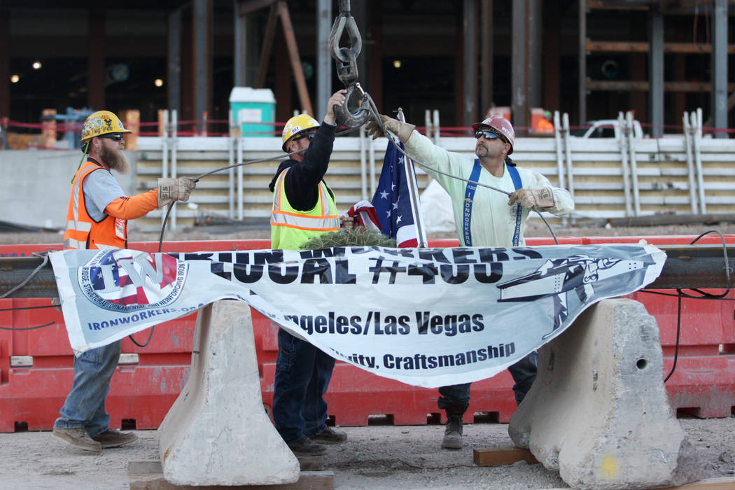 Workers secure a beam during a topping-off ceremony for the Expo at World Market Center in Las ...