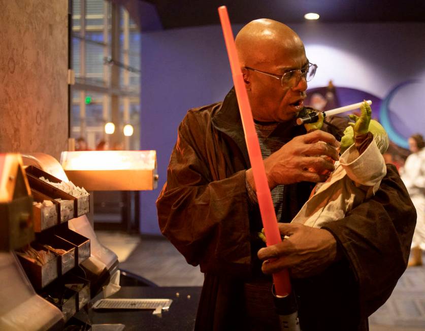 George R. Addison III pretends to feed his Yoda doll at the Star Wars: The Rise of Skywalker pr ...