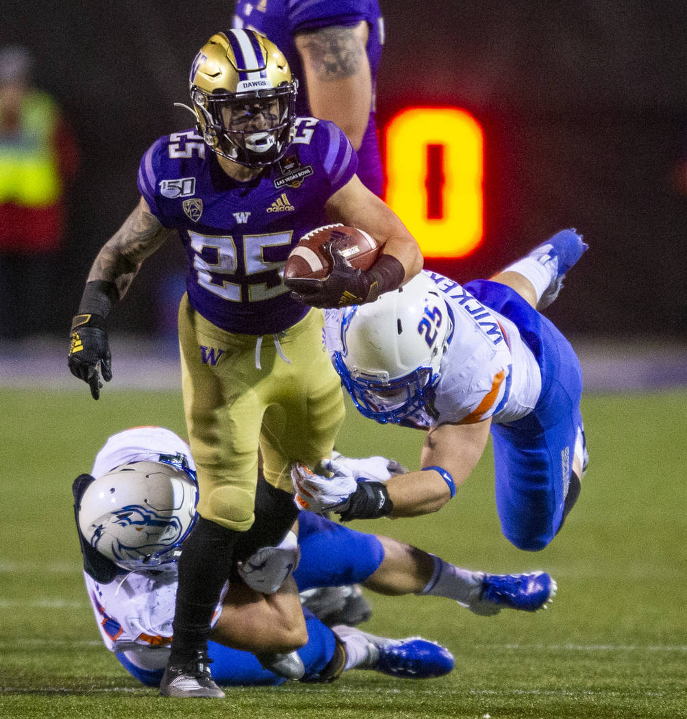 Washington Huskies running back Sean McGrew (25, top) attempts to break a tackle from Boise Sta ...