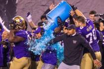 Washington Huskies head coach Chris Petersen, center, is soaked with Powerade and ice ending th ...