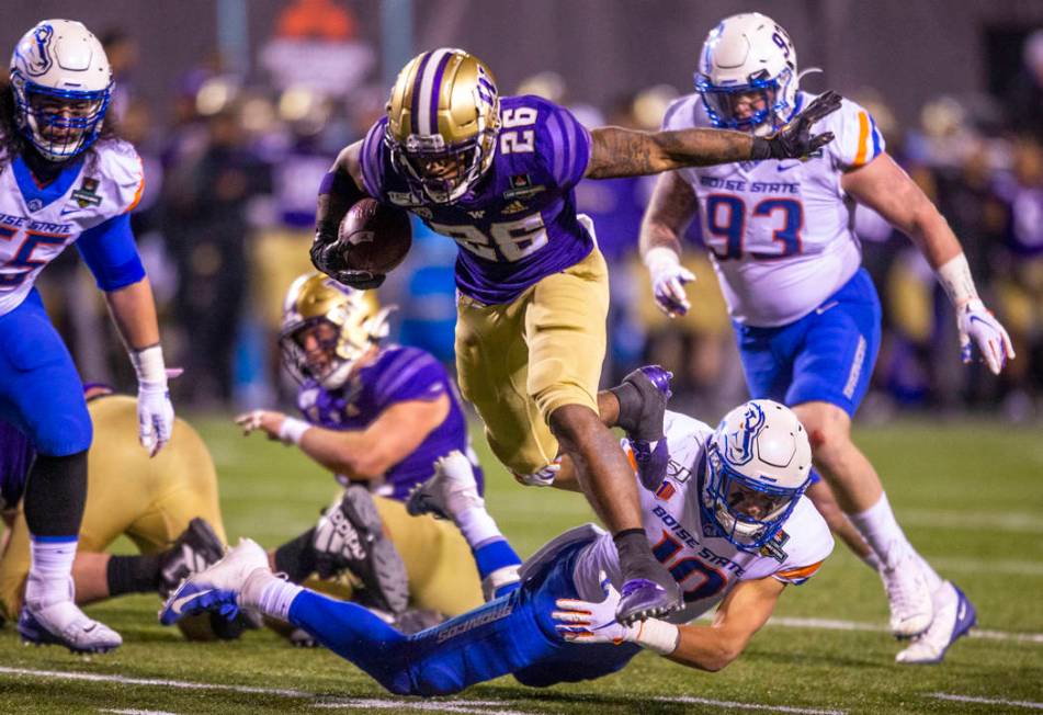 Washington Huskies running back Salvon Ahmed (26, tops) breaks free from a diving tackle attemp ...
