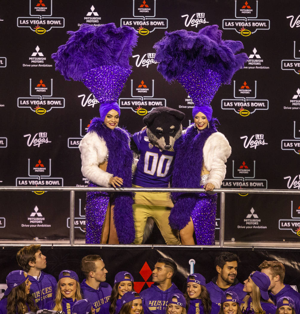 Washington Huskies mascot Harry the Husky poses with two showgirls after defeating the Boise St ...
