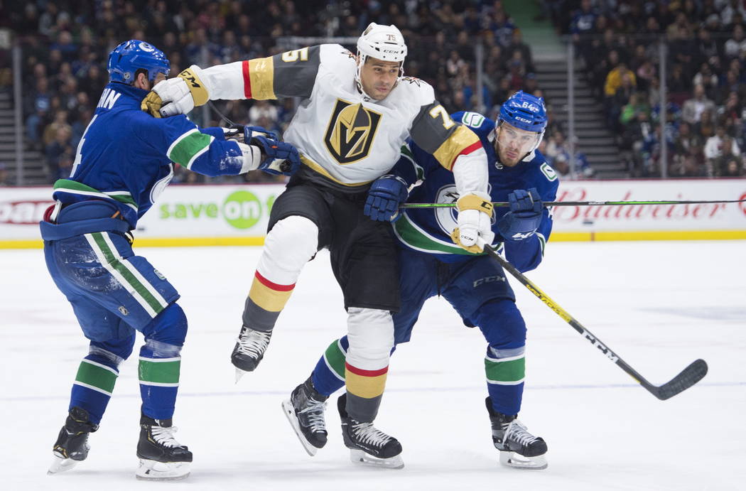 Vegas Golden Knights right wing Ryan Reaves (75) jumps to get past Vancouver Canucks defenseman ...