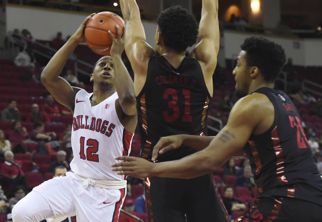 Fresno State's Mustafa Lawrence, left, goes up blocked by UNLV's Marvin Coleman, center, and Ni ...