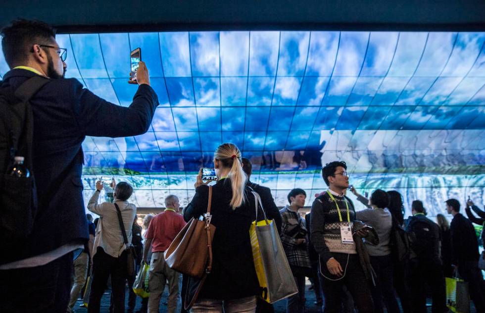 Convention goers watch a huge LG visual display in the North Hall of the Las Vegas Convention C ...