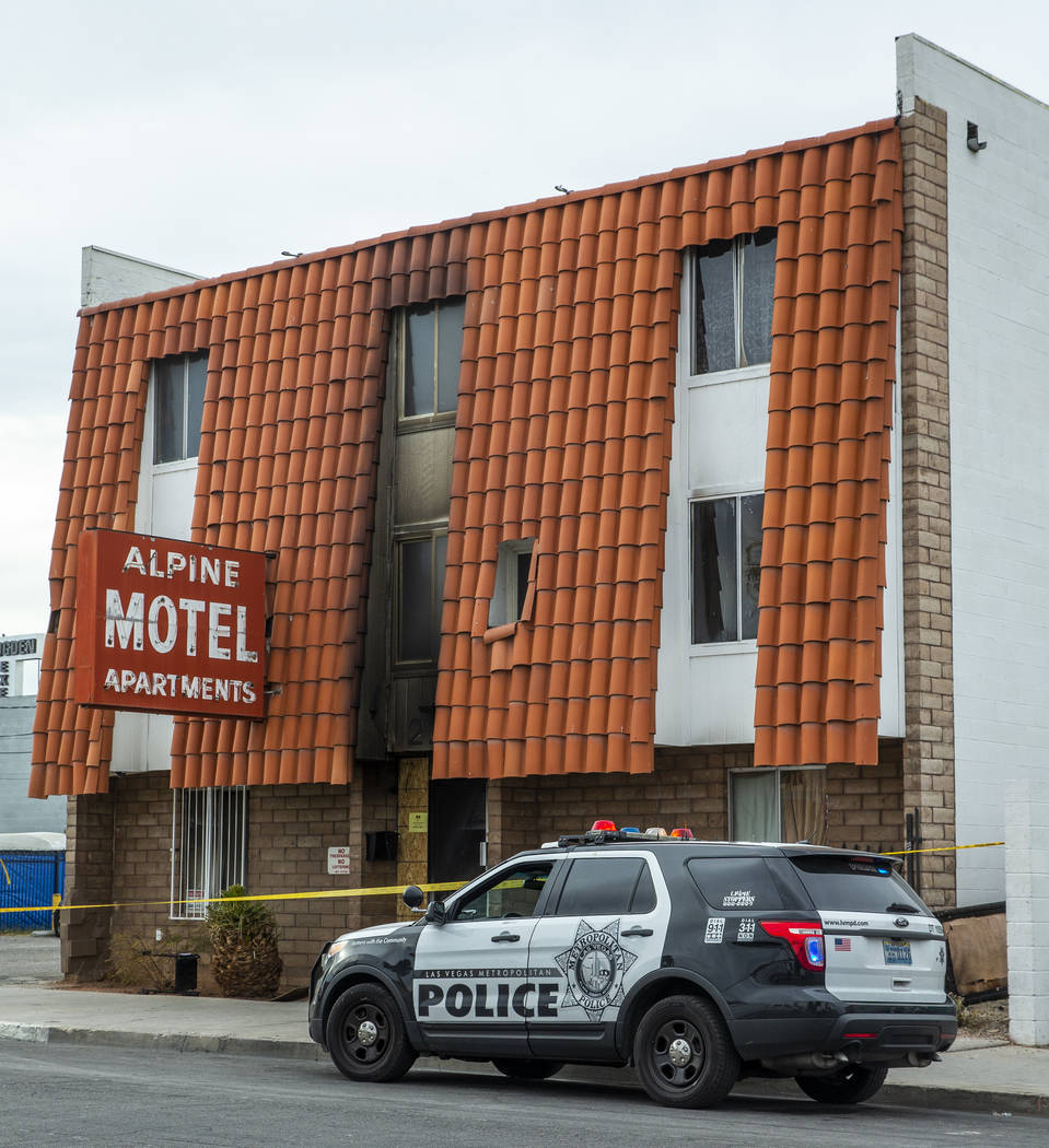 A Las Vegas police remains parked outside of the Alpine Motel Apartments with crime tape still ...