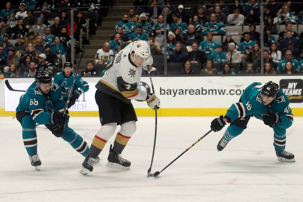 Vegas Golden Knights' Valentin Zykov, center, hits the puck between San Jose Sharks center Melk ...