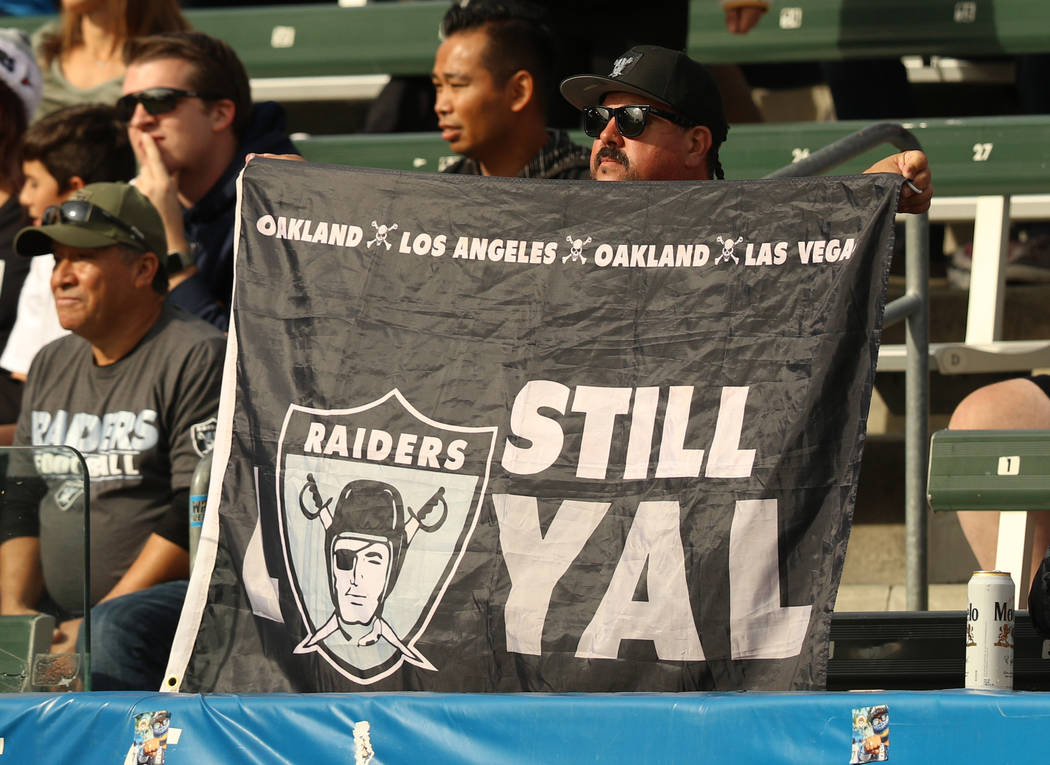 An Oakland Raiders fan holds up a flag showing all the cities the team has and will play in dur ...