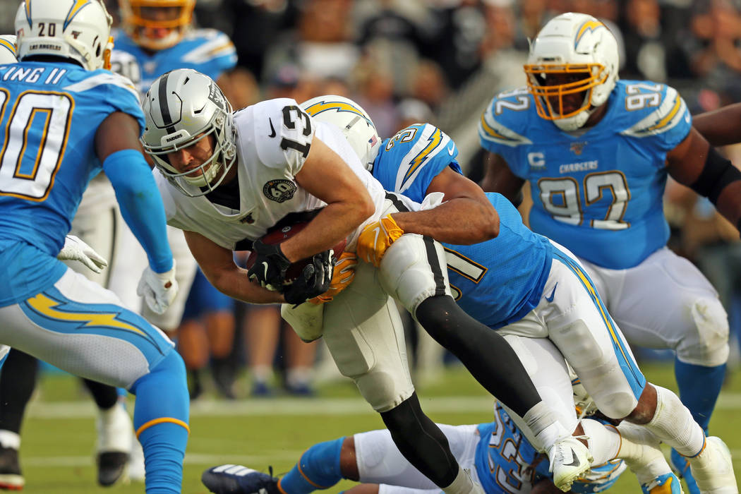 Oakland Raiders wide receiver Hunter Renfrow (13) is swarmed by Los Angeles Chargers defensive ...
