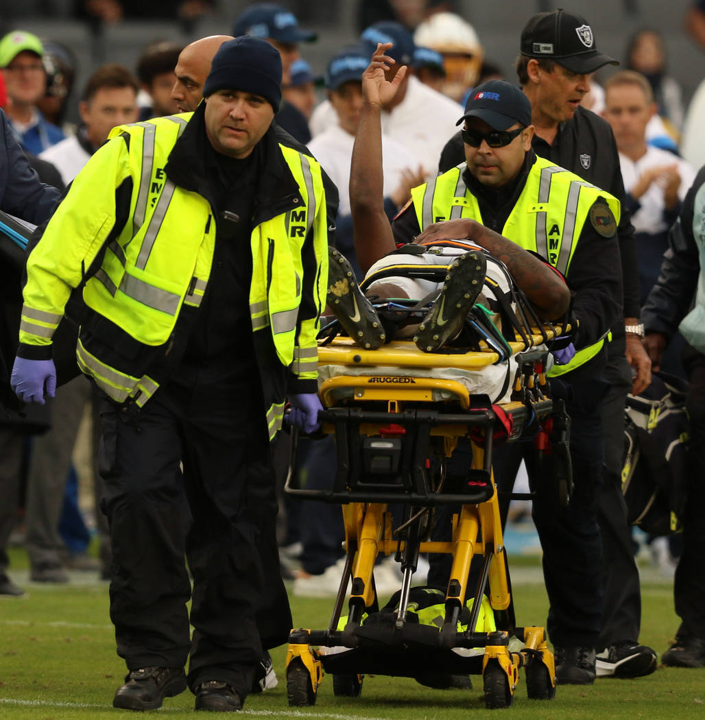 Oakland Raiders cornerback Trayvon Mullen reaches up to signal he is okay as he is carted off t ...