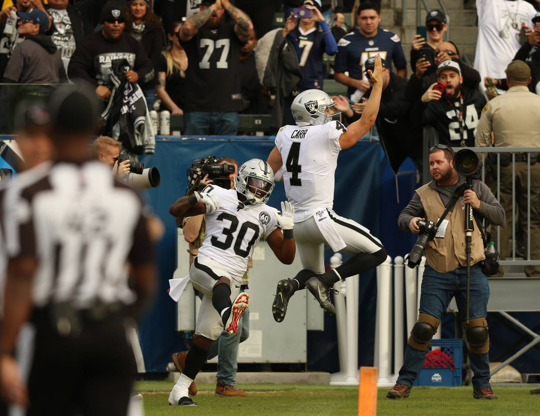 Oakland Raiders quarterback Derek Carr (4) celebrates his touchdown with running back Jalen Ric ...