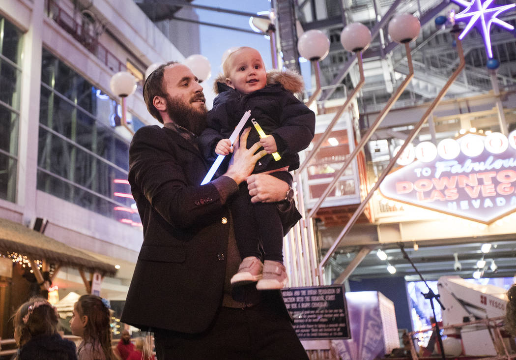 Rabbi Motti Harlig holds his son Mendel Harlig, 2, at a menorah lighting hosted by the Chabad o ...