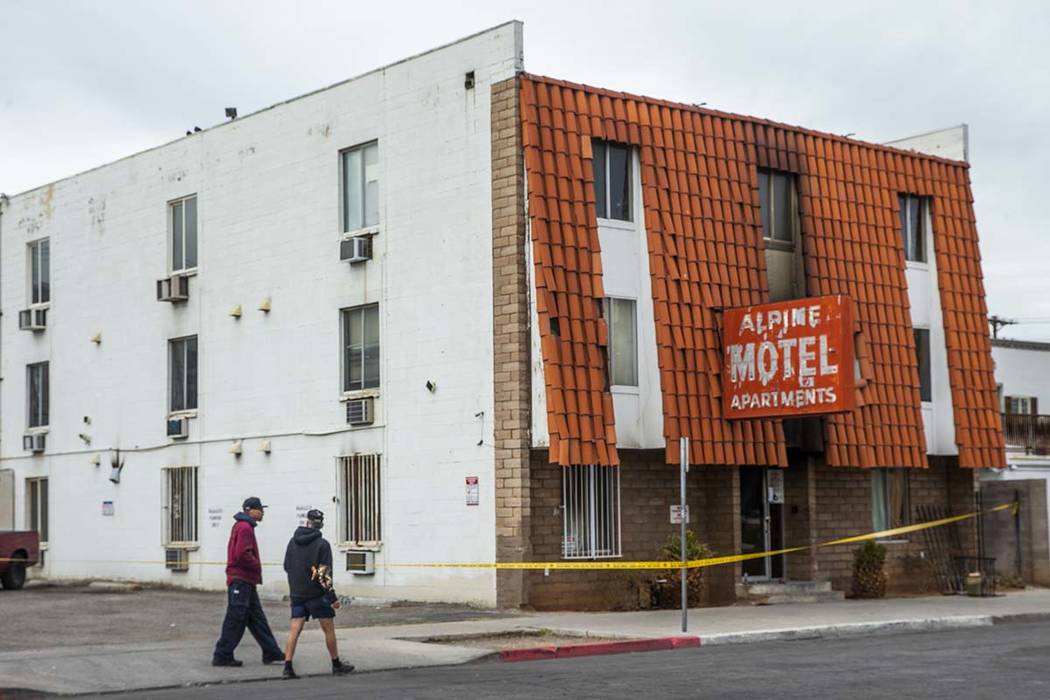 Pedestrians walk past the Alpine Apartment Motel with crime tape still in place on Sunday, Dec. ...