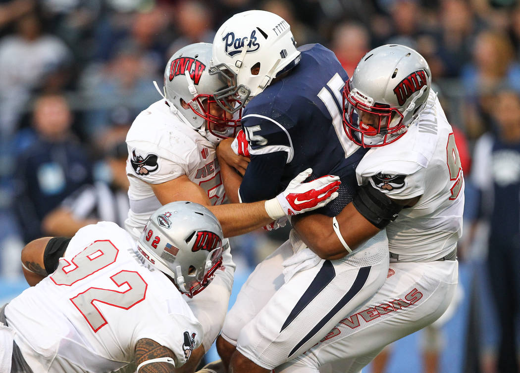 UNR's Tyler Stewart (15) is taken down by UNLV defensive players, from left, Salanoa-Alo Wily, ...