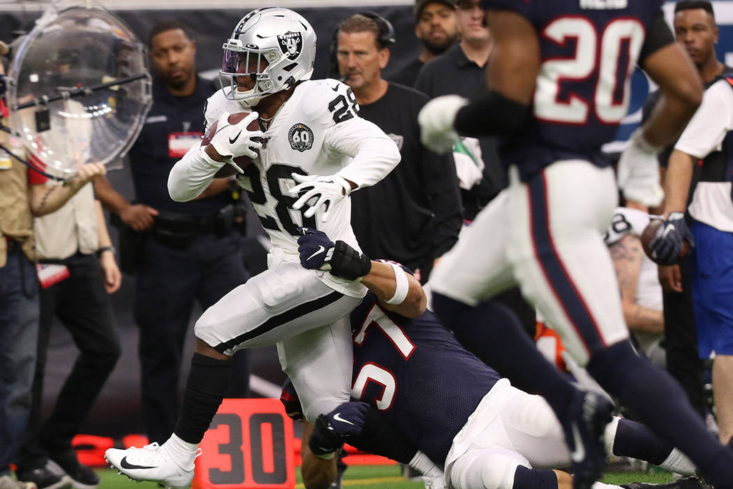 Oakland Raiders running back Josh Jacobs (28) tries to shed a tackle from Houston Texans outsid ...