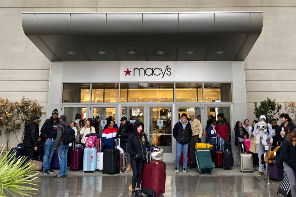 People shelter from the rain at the door to Macy's at Fashion Show mall in Las Vegas as they wa ...