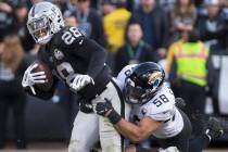 Oakland Raiders running back Josh Jacobs (28) drags Jacksonville Jaguars outside linebacker Aus ...