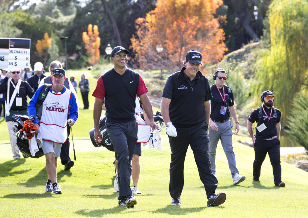 Tiger Woods, left, and Phil Mickelson walk to the fairway after teeing off from the first durin ...