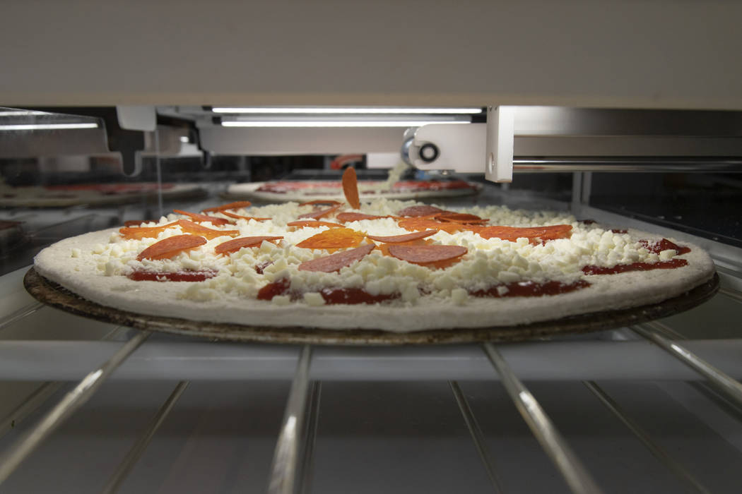 The robotic system adds pepperoni. (Picnic)